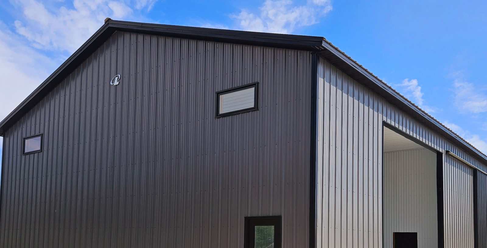 Agricultural post-frame machine shed with dark metal siding