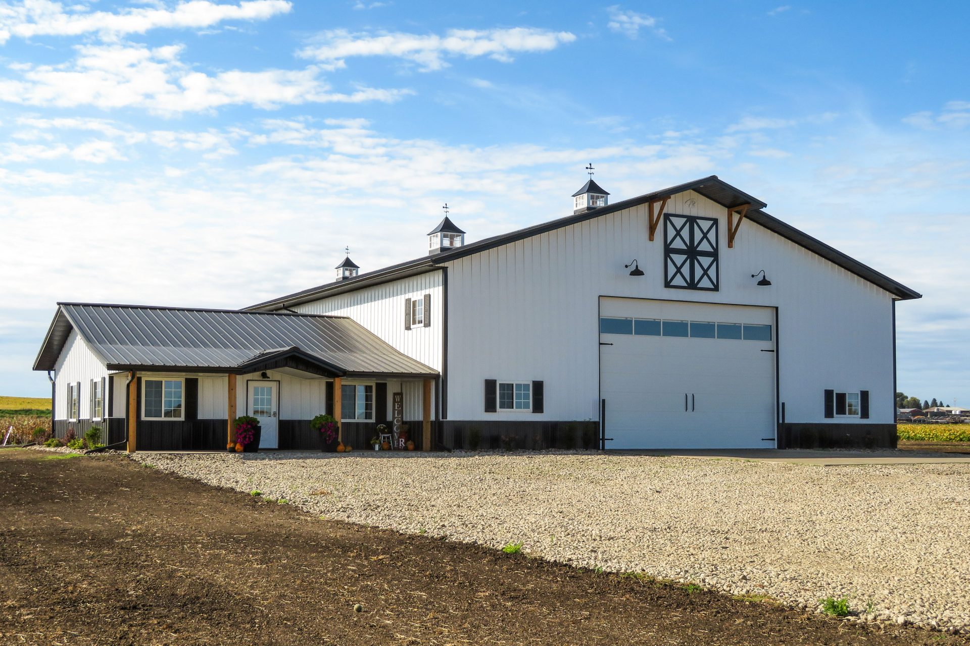 Custom white and black post-frame barndominium with cupolas built by Hoksbergen & De Stigter